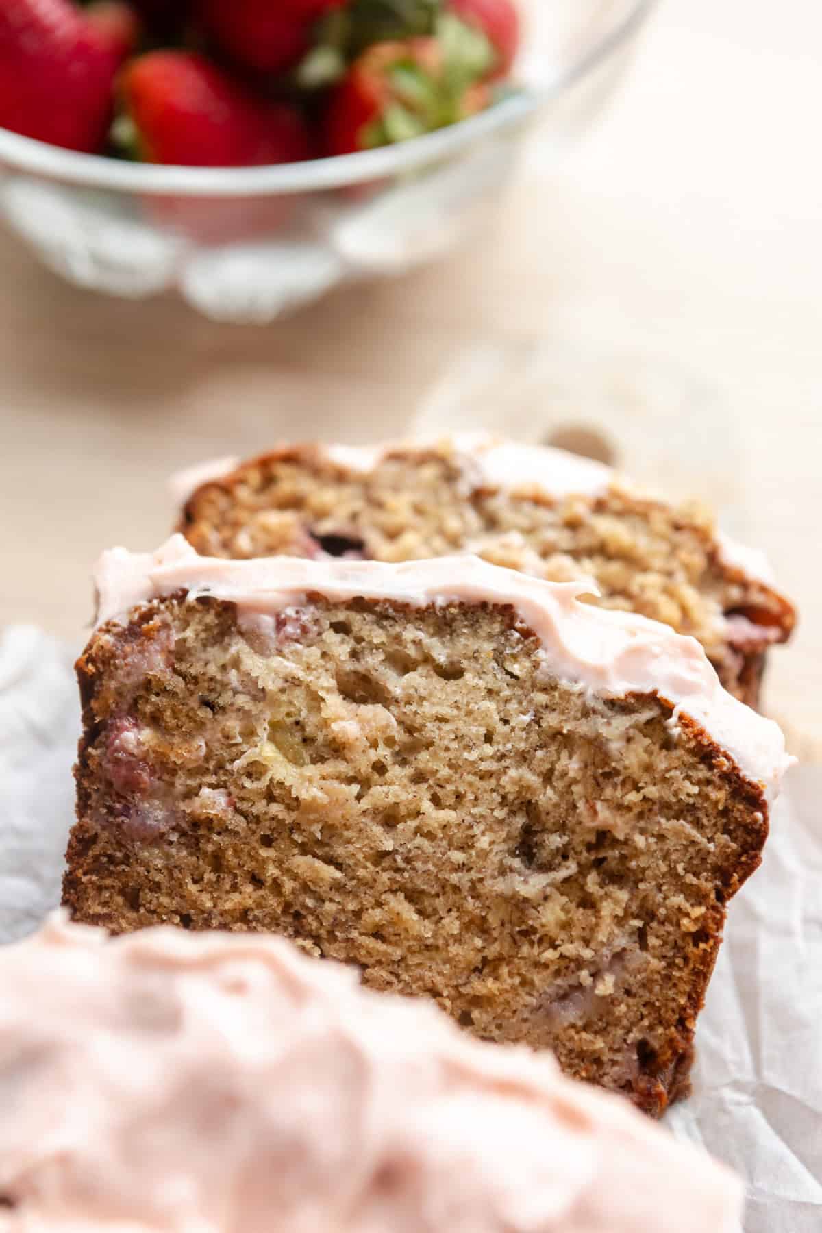 Slices of strawberry banana bread with cream cheese frosting.