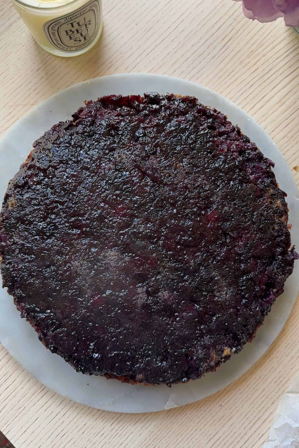 A blueberry upside down cake on a marble cake stand.