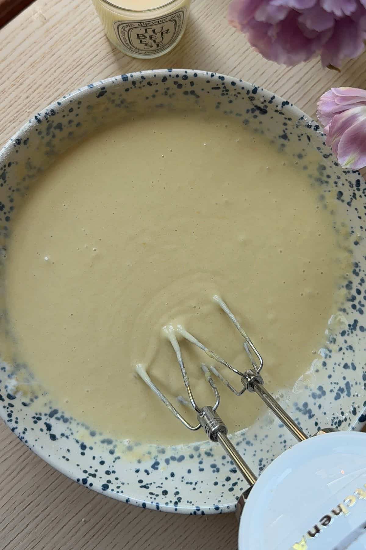 Cake batter in a large mixing bowl with a hand mixer.