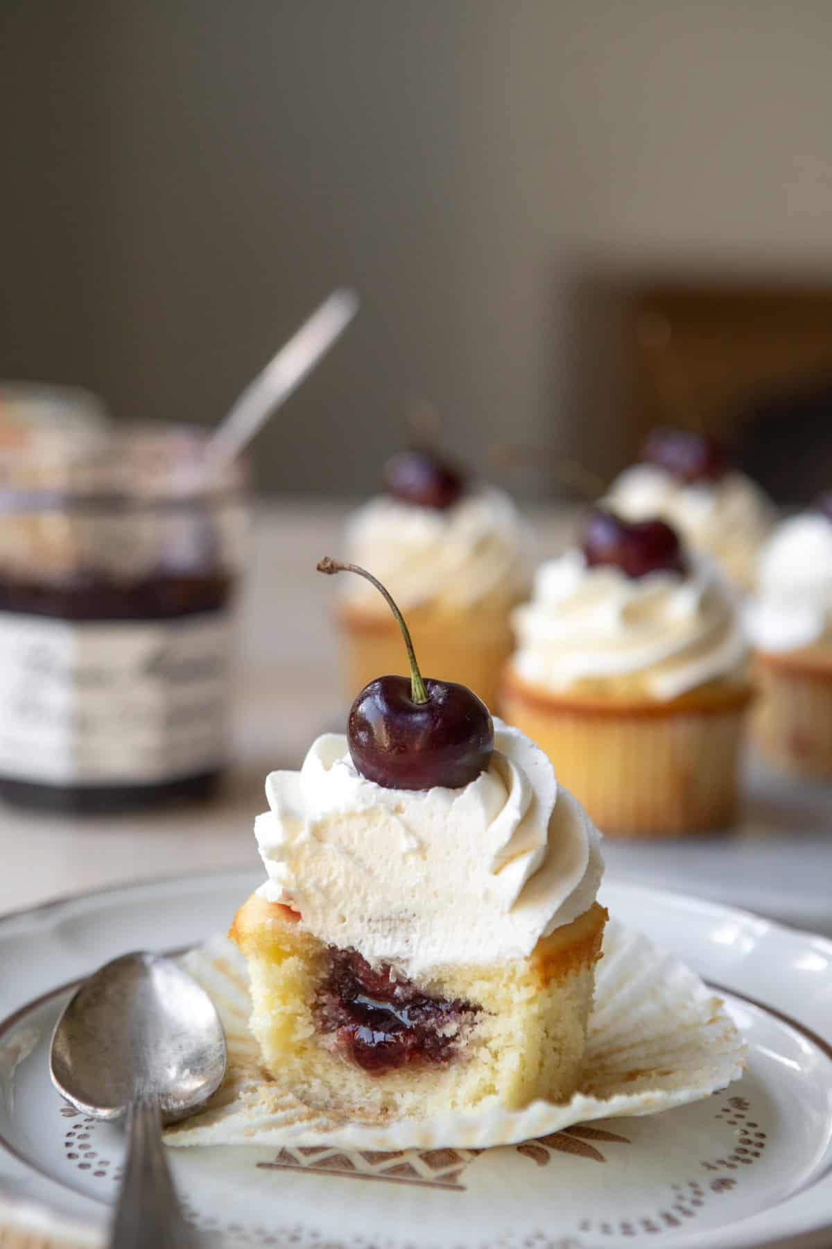 A cherry almond cupcake on a plate cut open to show cherry jam texture.