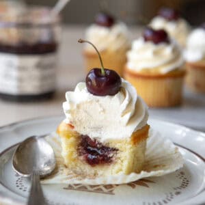 Cherry almond cupcakes on a plate with on cut open.