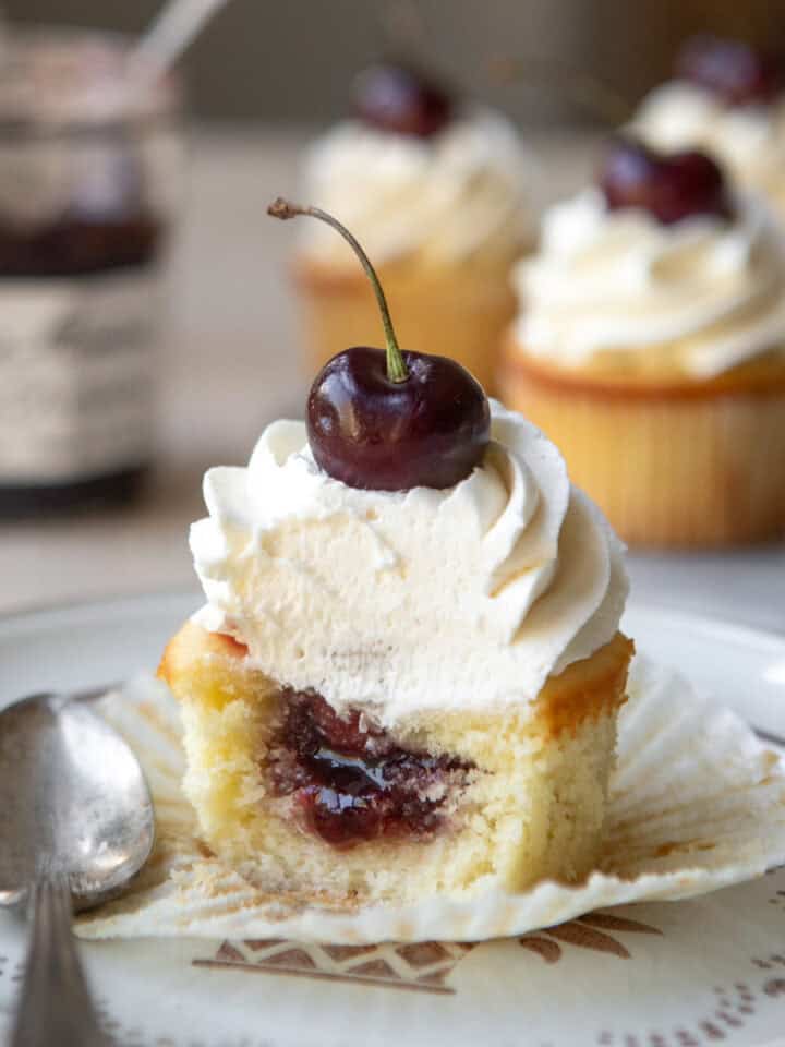 Cherry almond cupcakes on a plate with on cut open.