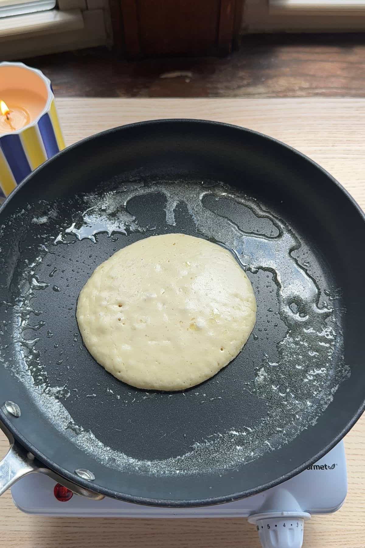 A pancake cooking in a pan.