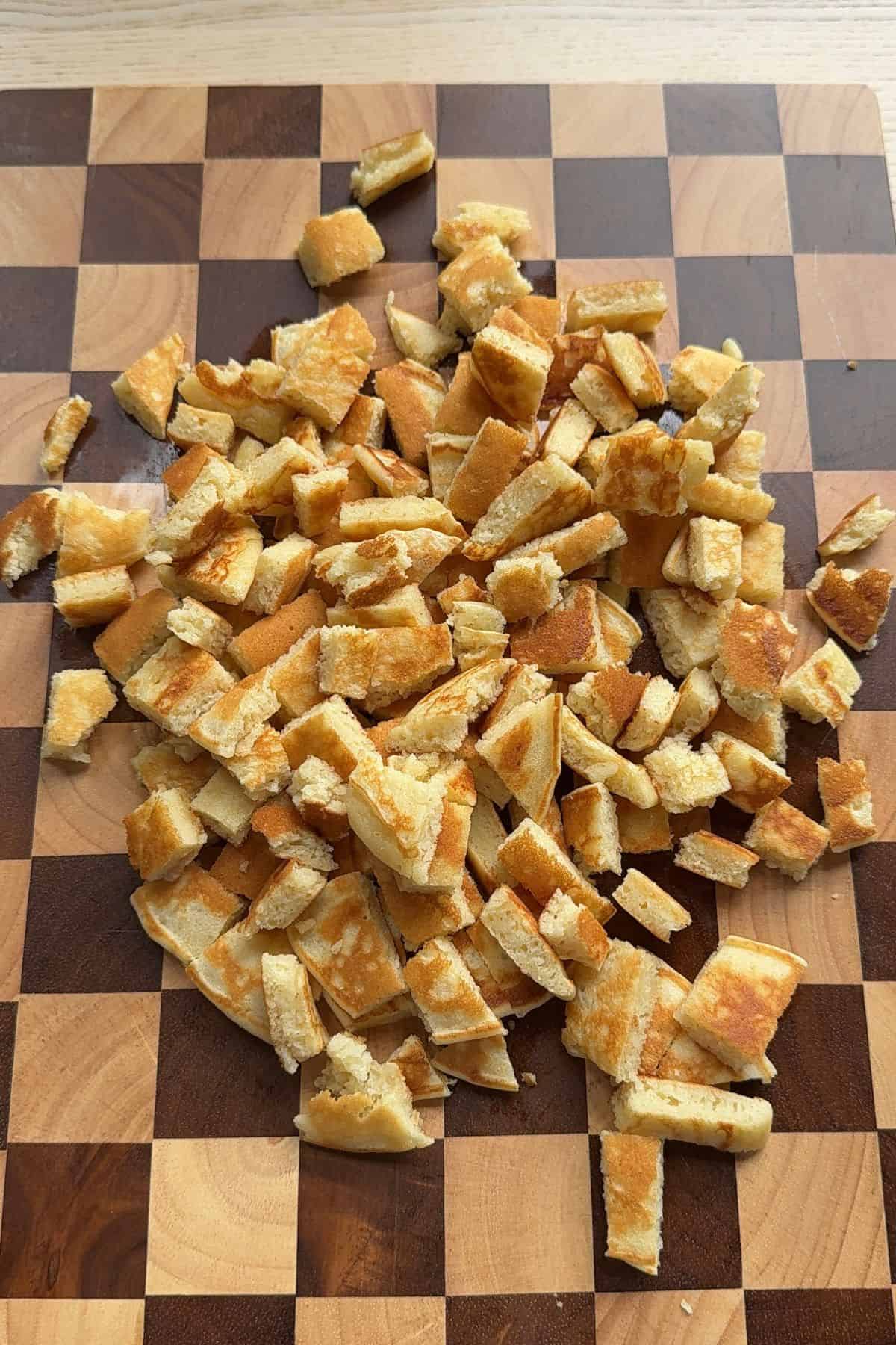 Cut up pancakes on a checkered cutting board.