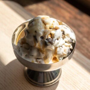 A scoop of pancake flavored ice cream in a metal bowl with chocolate chunks.