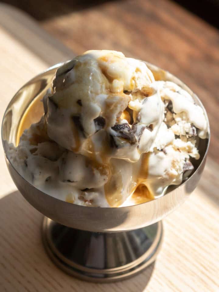 A scoop of pancake flavored ice cream in a metal bowl with chocolate chunks.