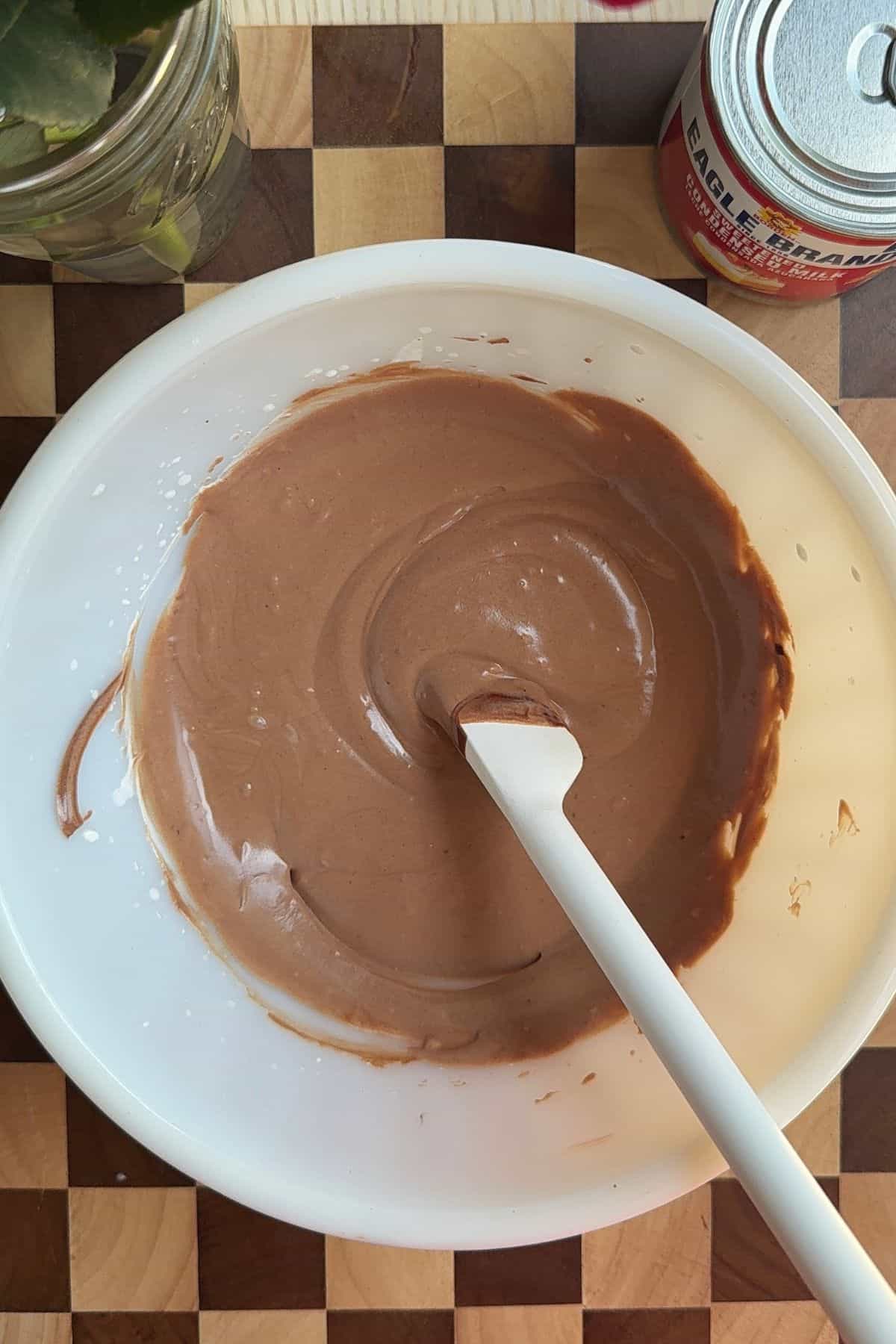 Chocolate mousse in a mixing bowl with a rubber spatula.