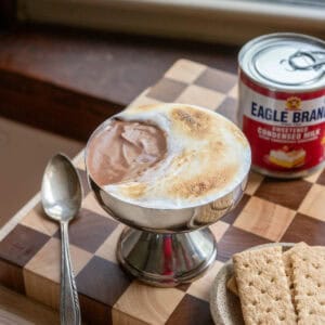 A chocolate mousse s'mores cup on a checkered cutting board.