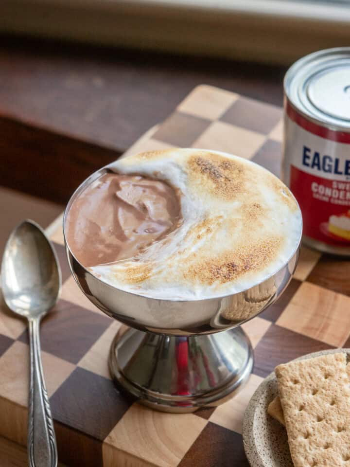 A chocolate mousse s'mores cup on a checkered cutting board.