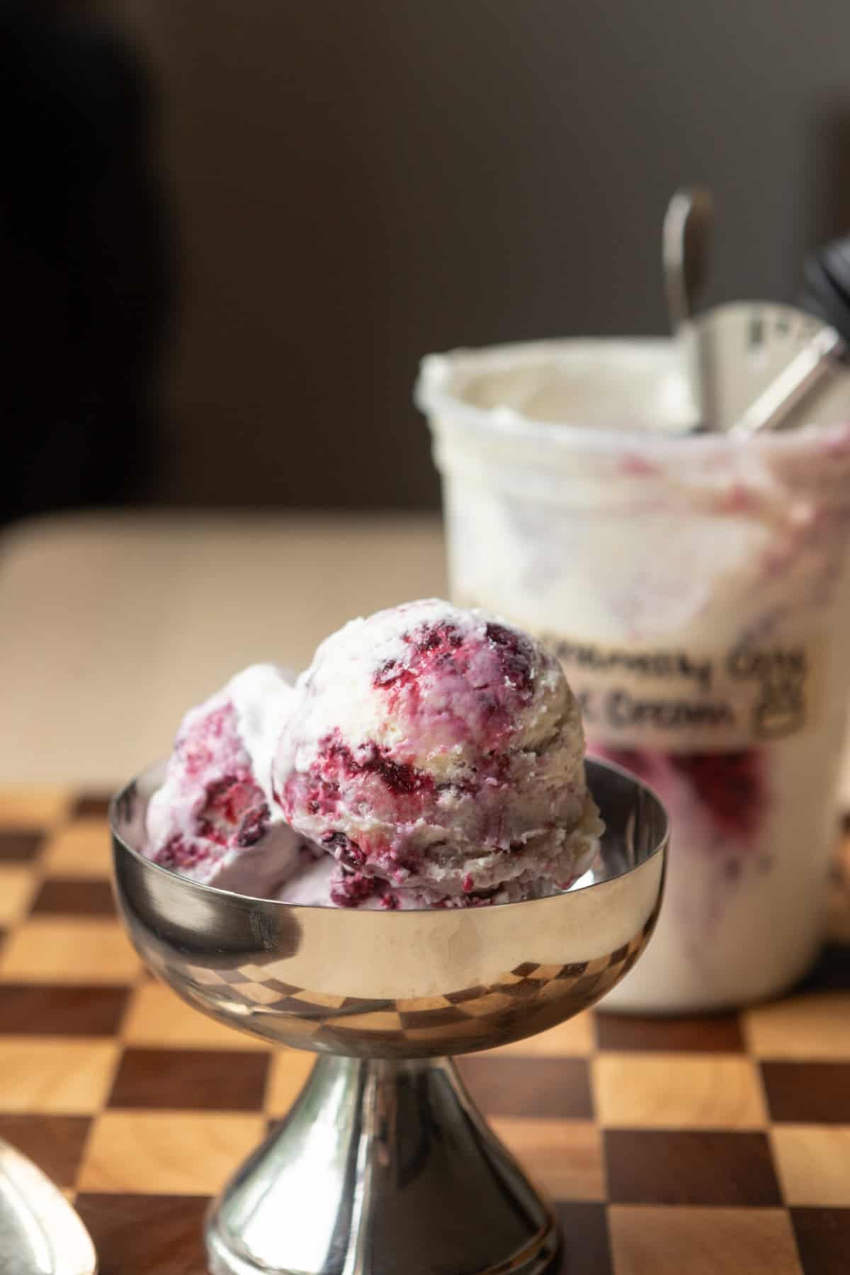 A stainless steel bowl with scoops of berry Chantilly cake batter ice cream inside.