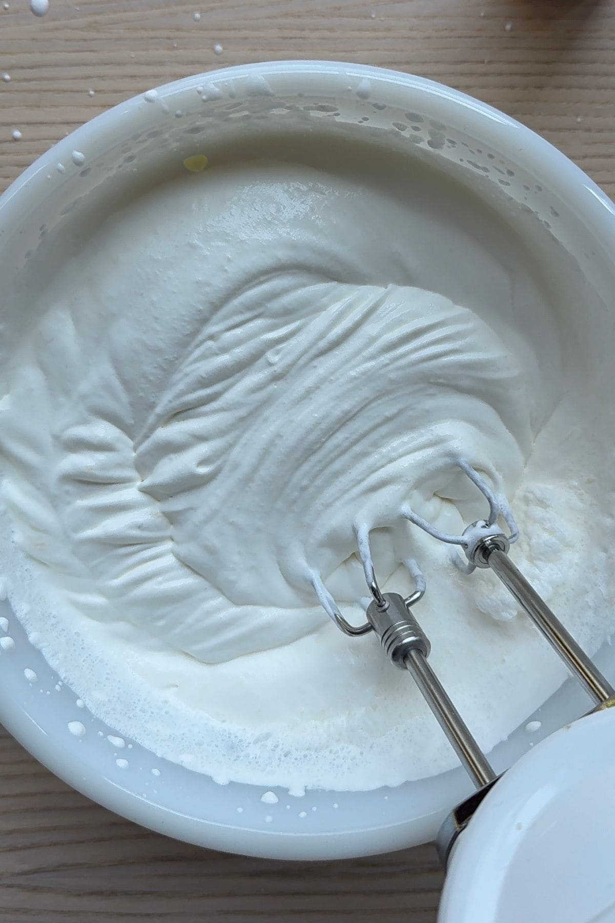Whipped cream in a bowl with electric mixer beaters.