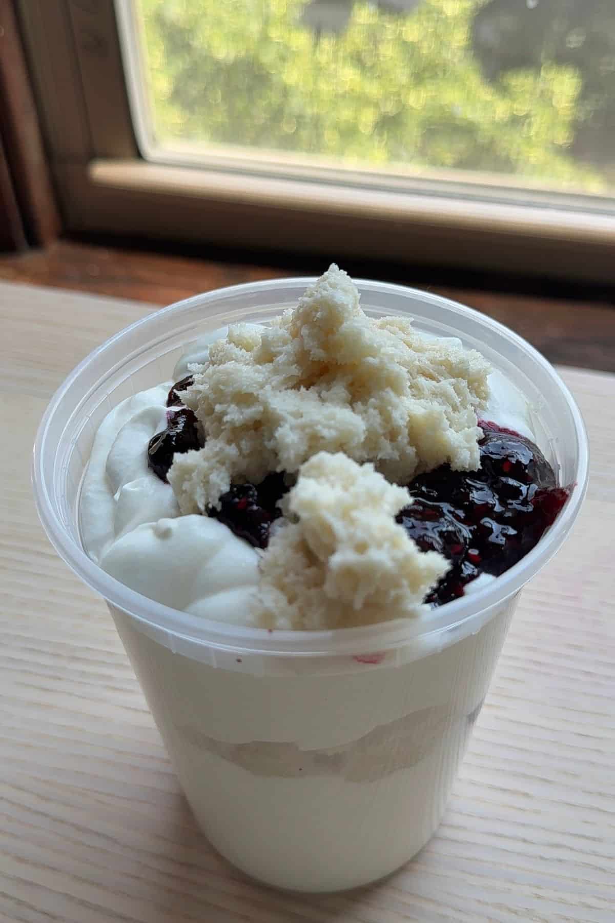 A deli container filled with ice cream base, jam, and cake batter pieces.