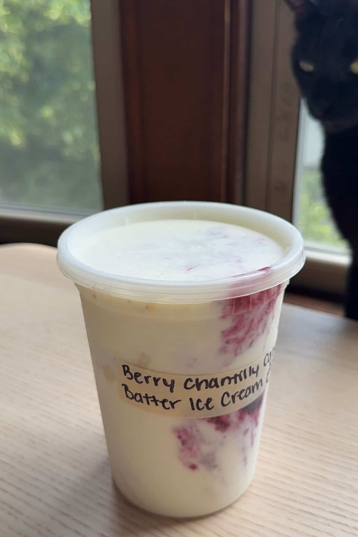 A deli container with a label that says "Berry Chantilly Cake Batter Ice Cream" on it.