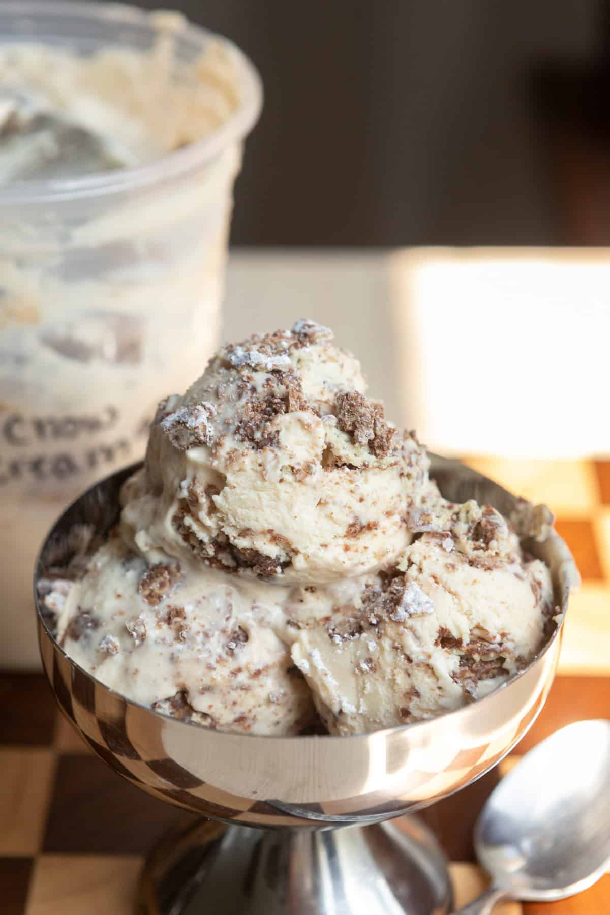 A close up of three scoops of ice cream in a metal dessert bowl.