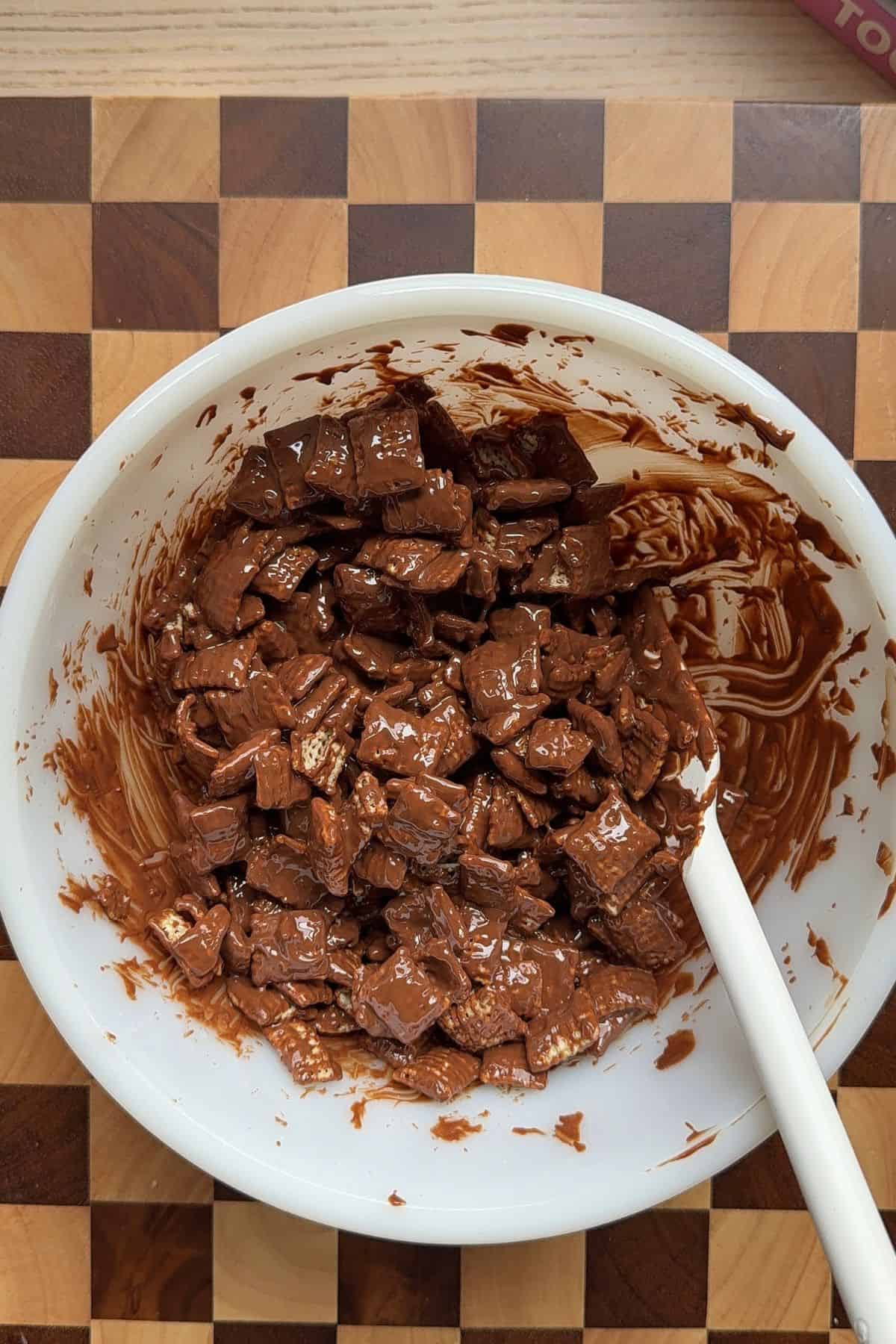 Chex cereal coated in melted chocolate and peanut butter in a bowl.