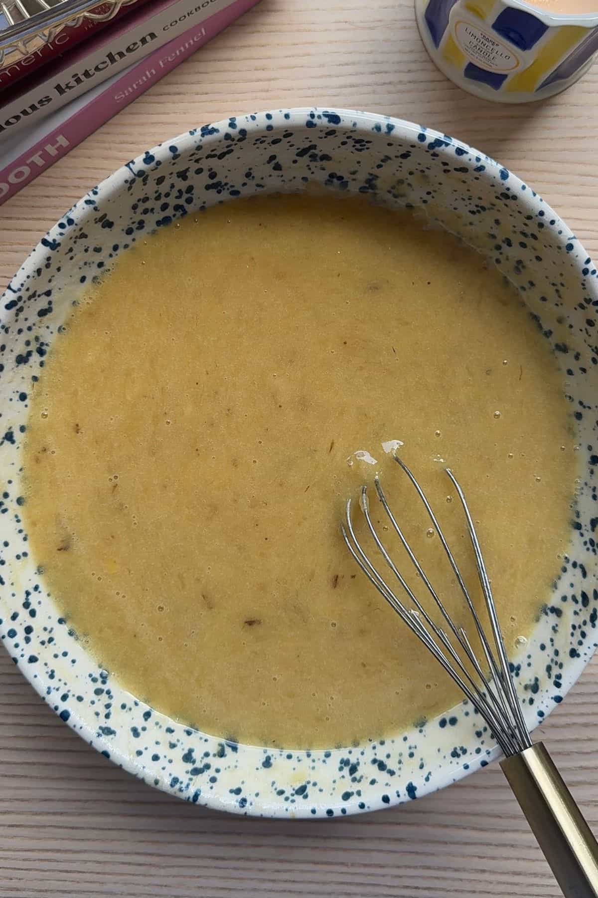 Wet ingredients for banana bread mixed in a bowl with a whisk.