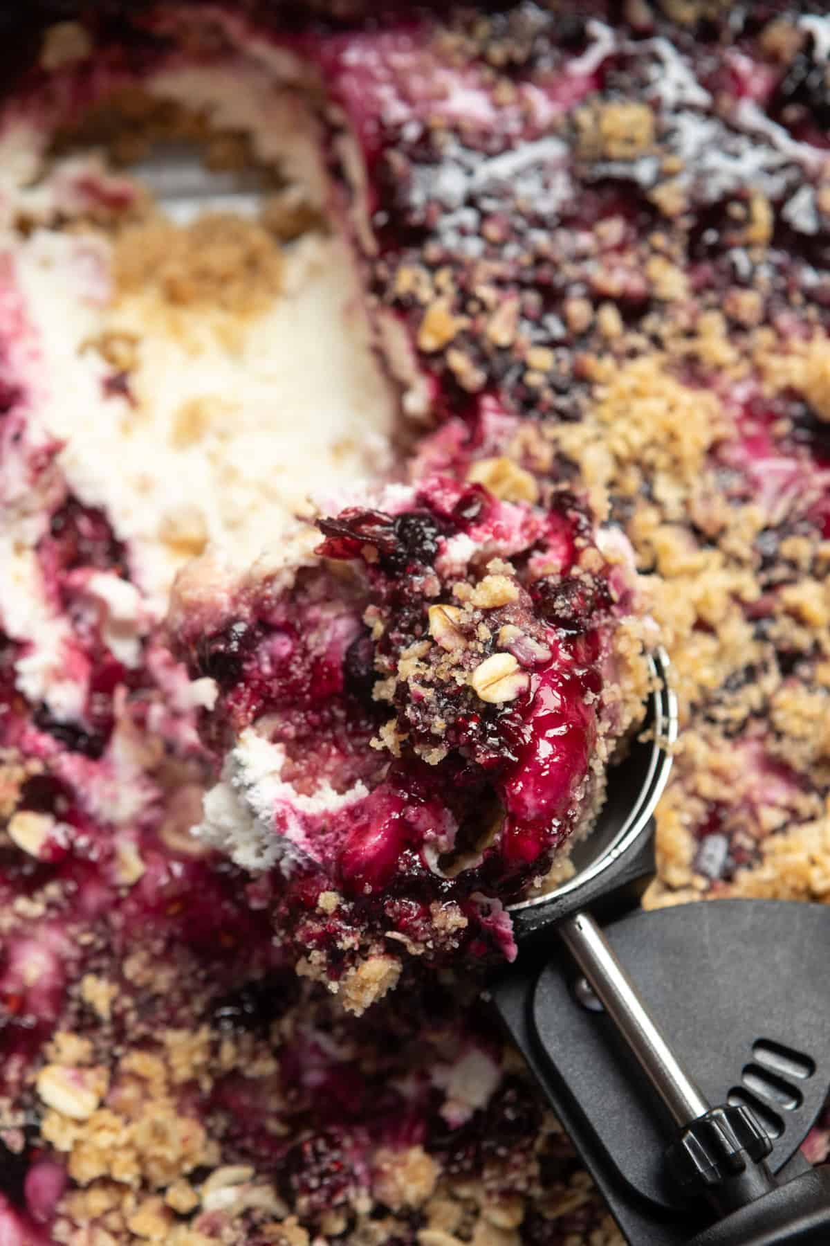 An ice cream scoop full of scoopable cheesecake in the pan.