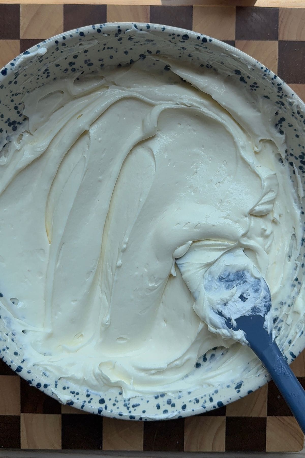 Cheesecake batter in a large bowl with a blue rubber spatula.