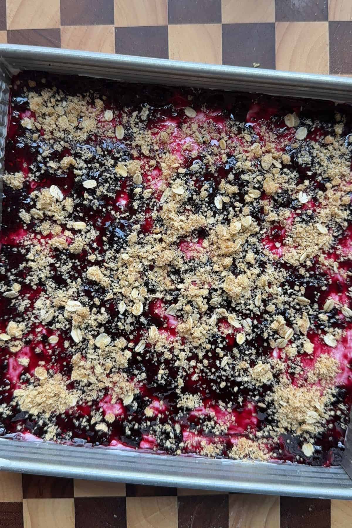 Berry crumble cheesecake in a square pan.