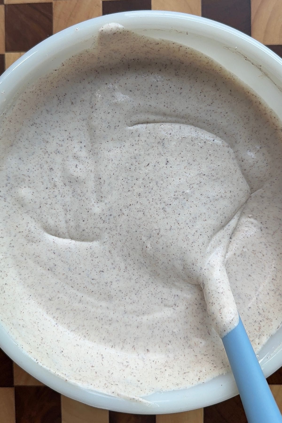 Whipped cream, cinnamon, and sweetened condensed milk folded together in a mixing bowl.
