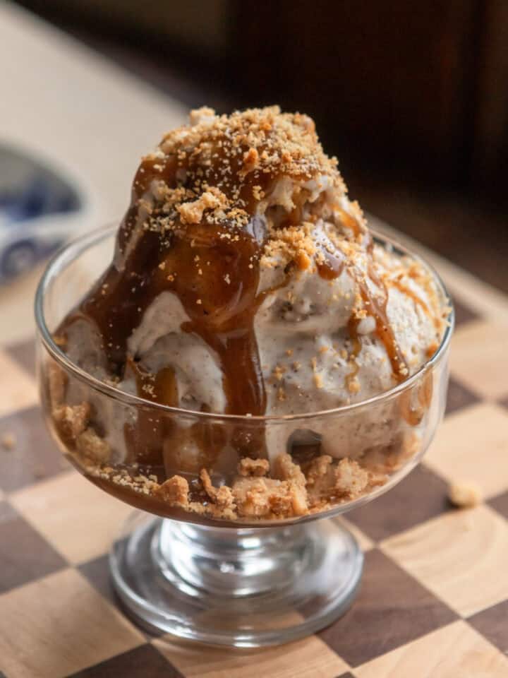 Scoops of brown sugar pop tart ice cream in a glass bowl with butterscotch and pie crust crumbs on top.