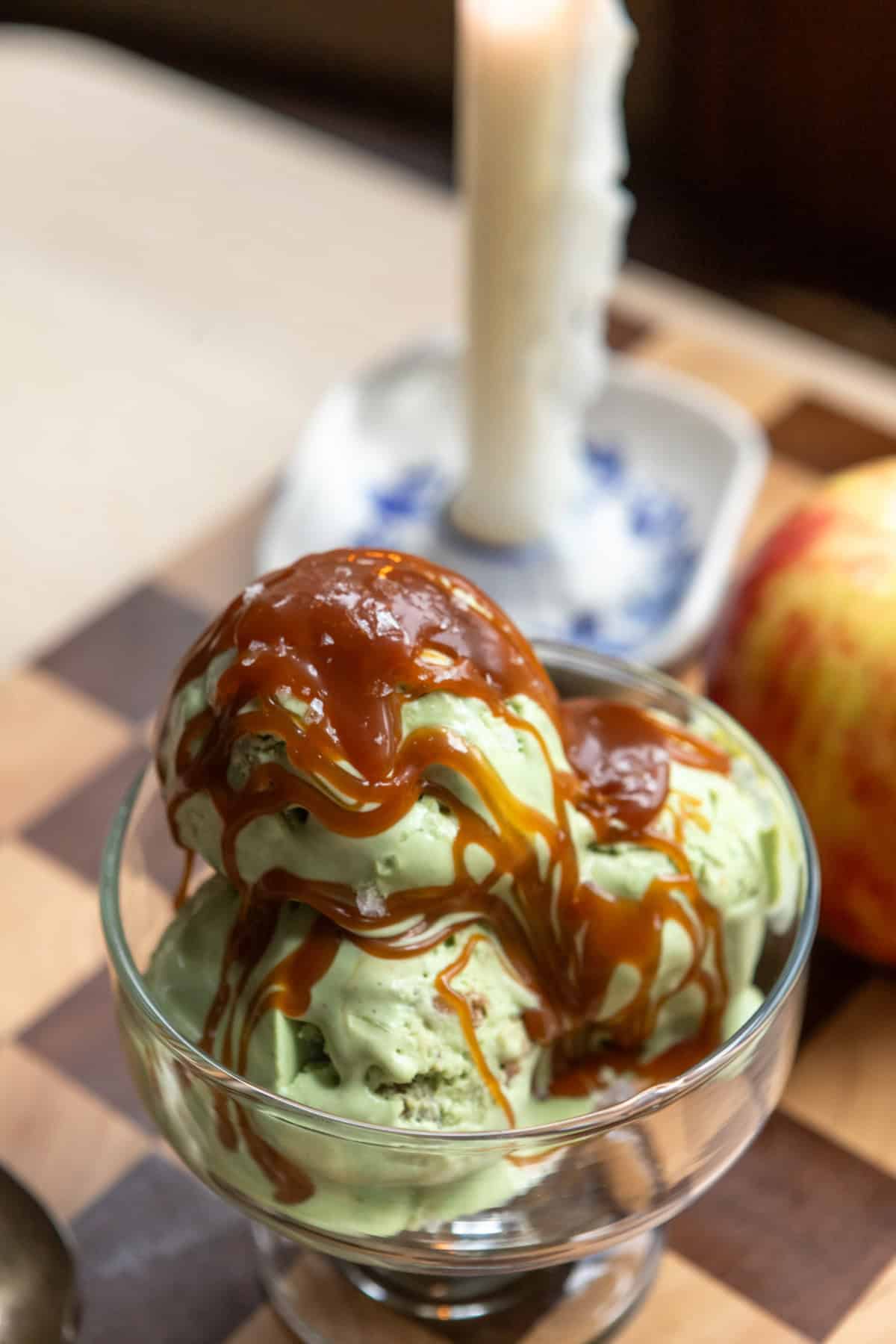 Matcha ice cream with a drizzle of caramel in a clear dish.