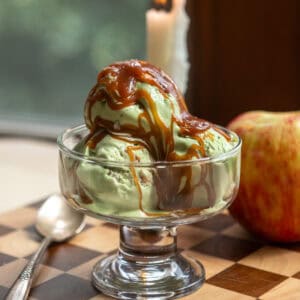 A clear glass dish with three scoops of caramel apple matcha ice cream in it.
