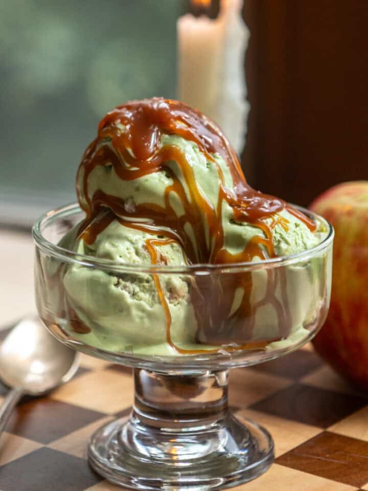 A clear glass dish with three scoops of caramel apple matcha ice cream in it.