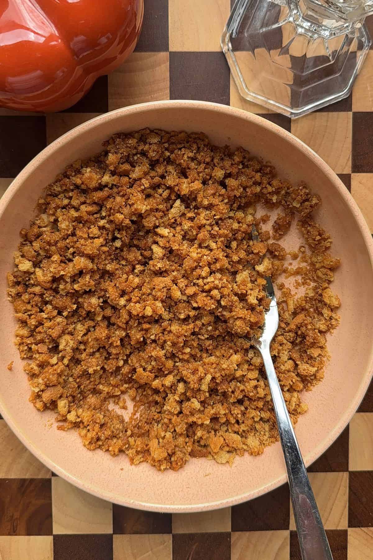 Gingersnap crumbs in a bowl with a fork.