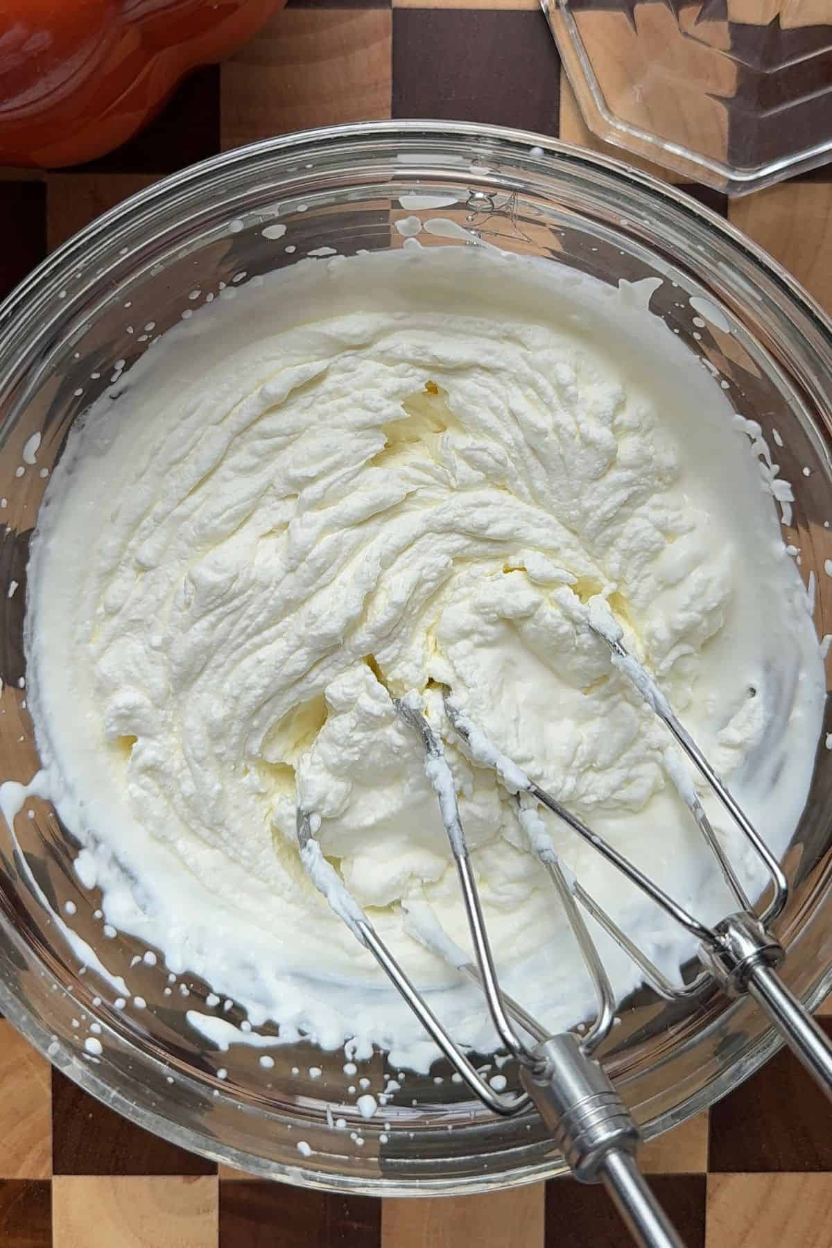 Whipped cream in a glass mixing bowl.