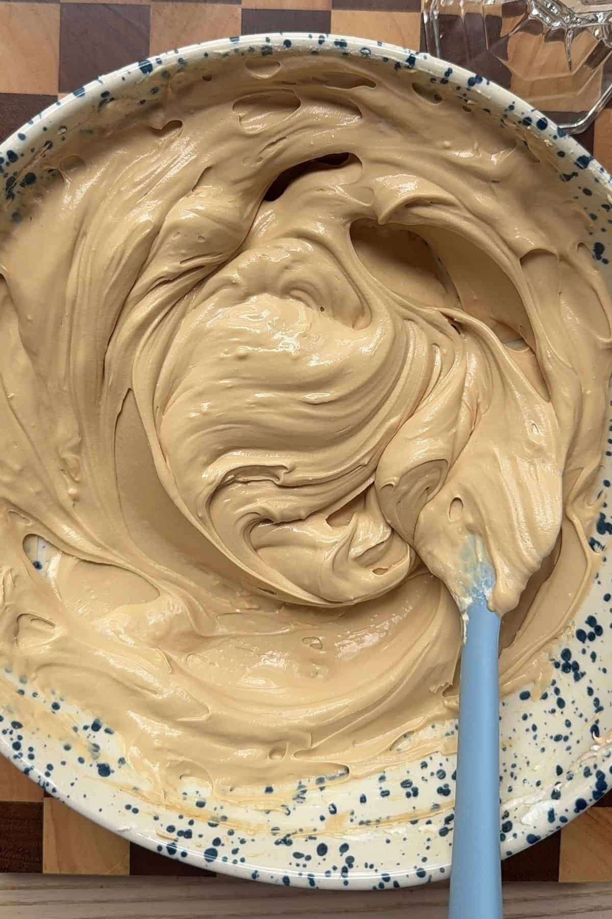 No bake coffee cheesecake batter in a speckled bowl with a rubber spatula.