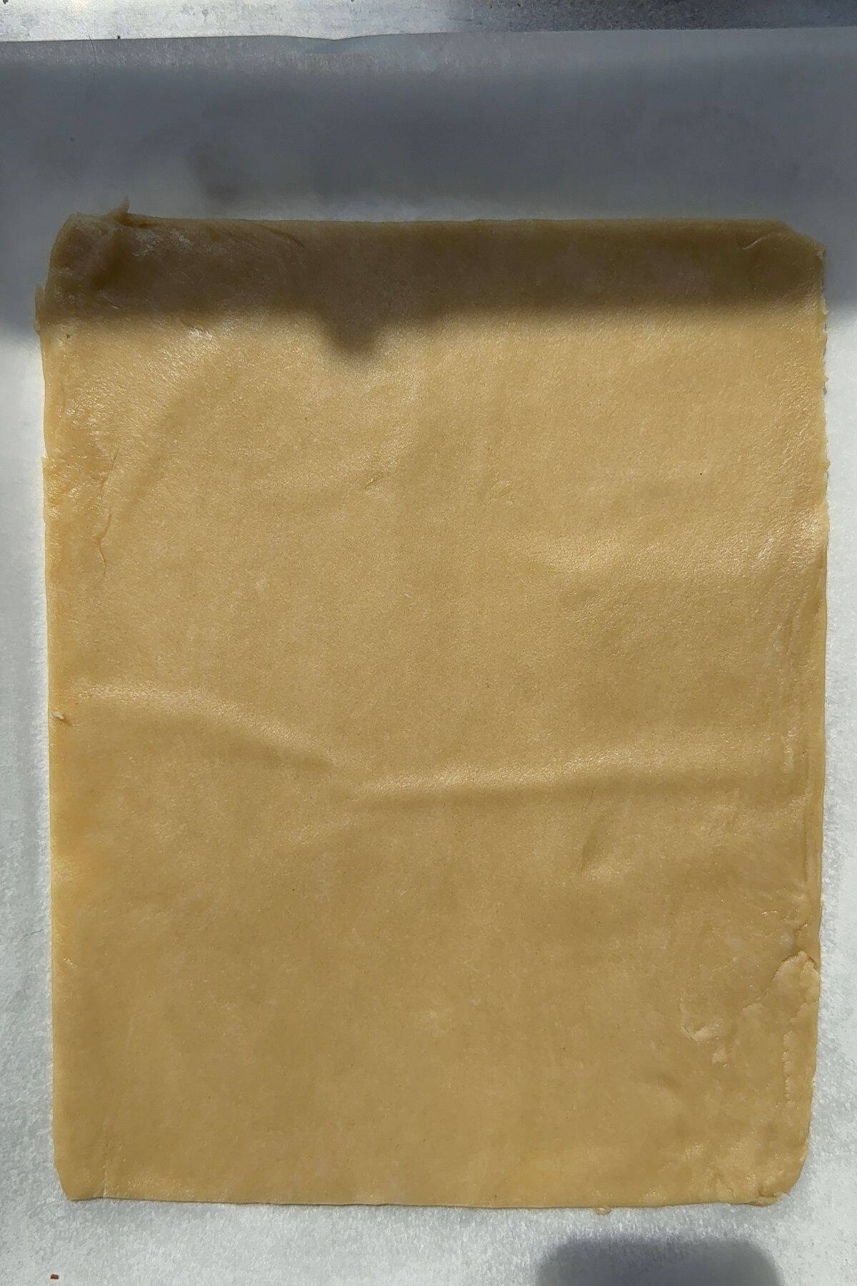 A rectangle sheet of pie dough on a baking pan.