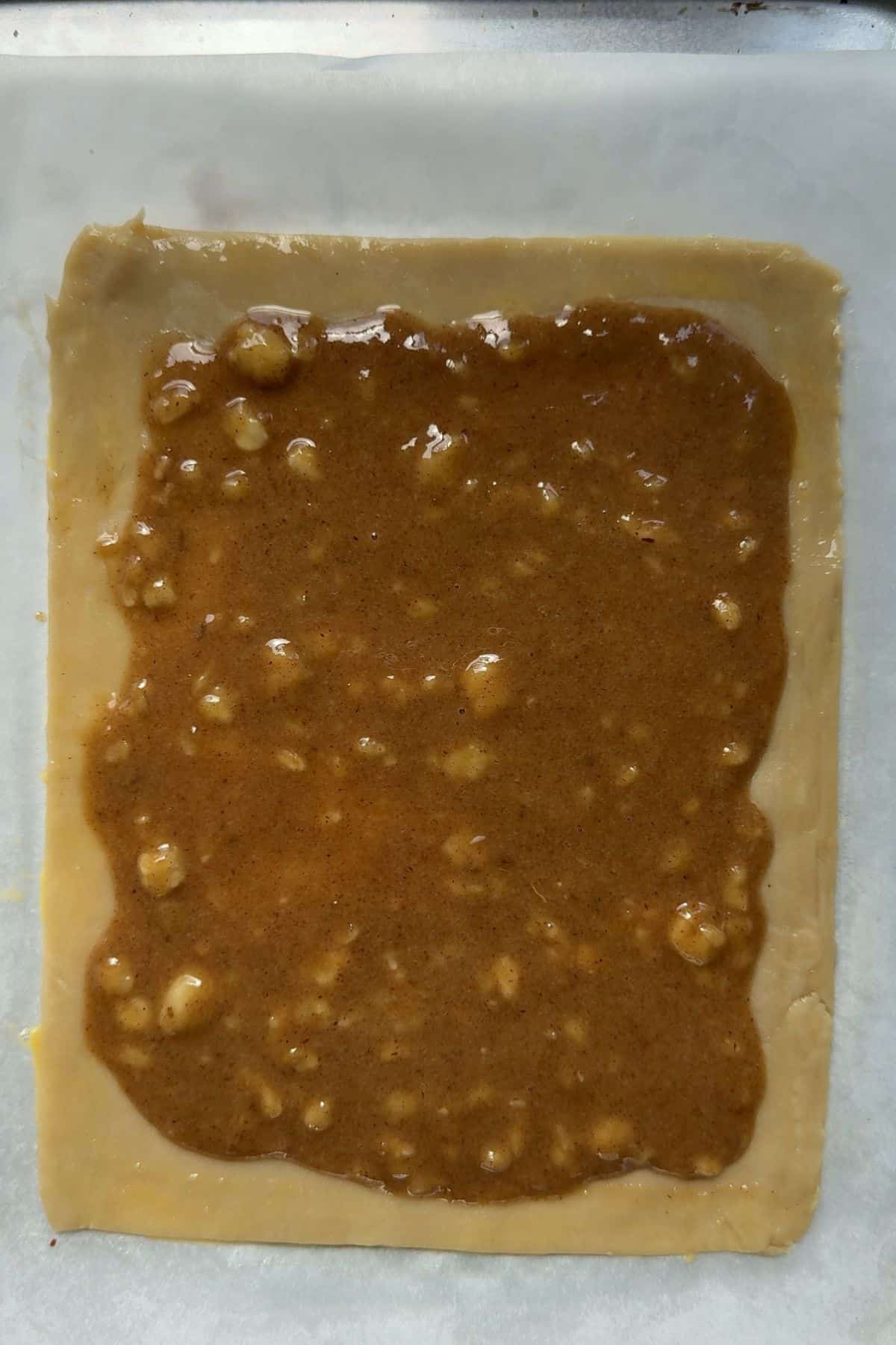 Banana bread filling spooned on top of a rectangle sheet of pie dough.