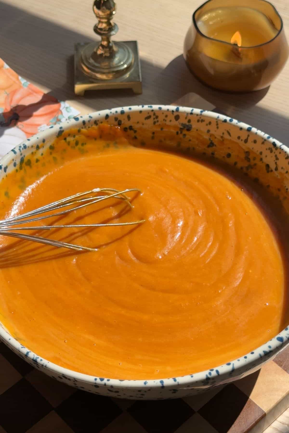 Pumpkin bread batter in a large speckled mixing bowl with a whisk.