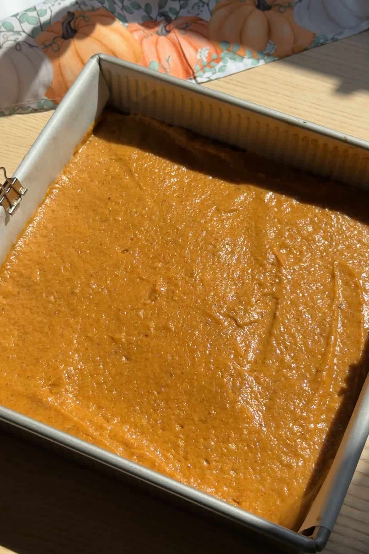Unbaked pumpkin bar batter in a square pan.