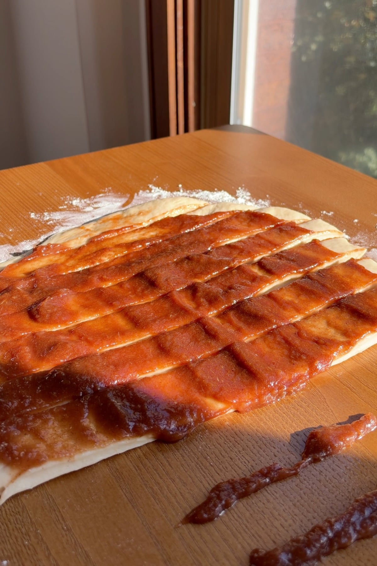 Dough covered in apple butter cut into strips.
