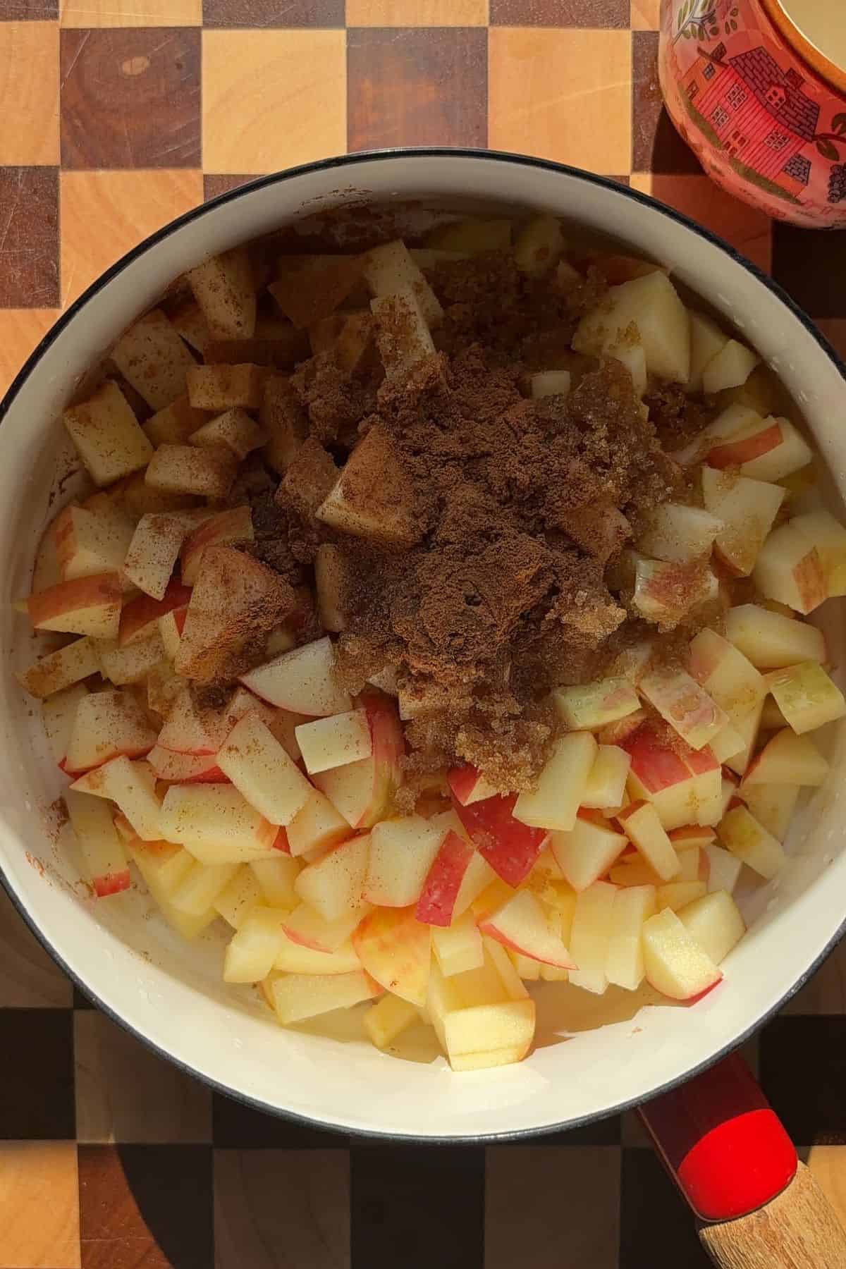 Apple chunks and spices in a saucepan.