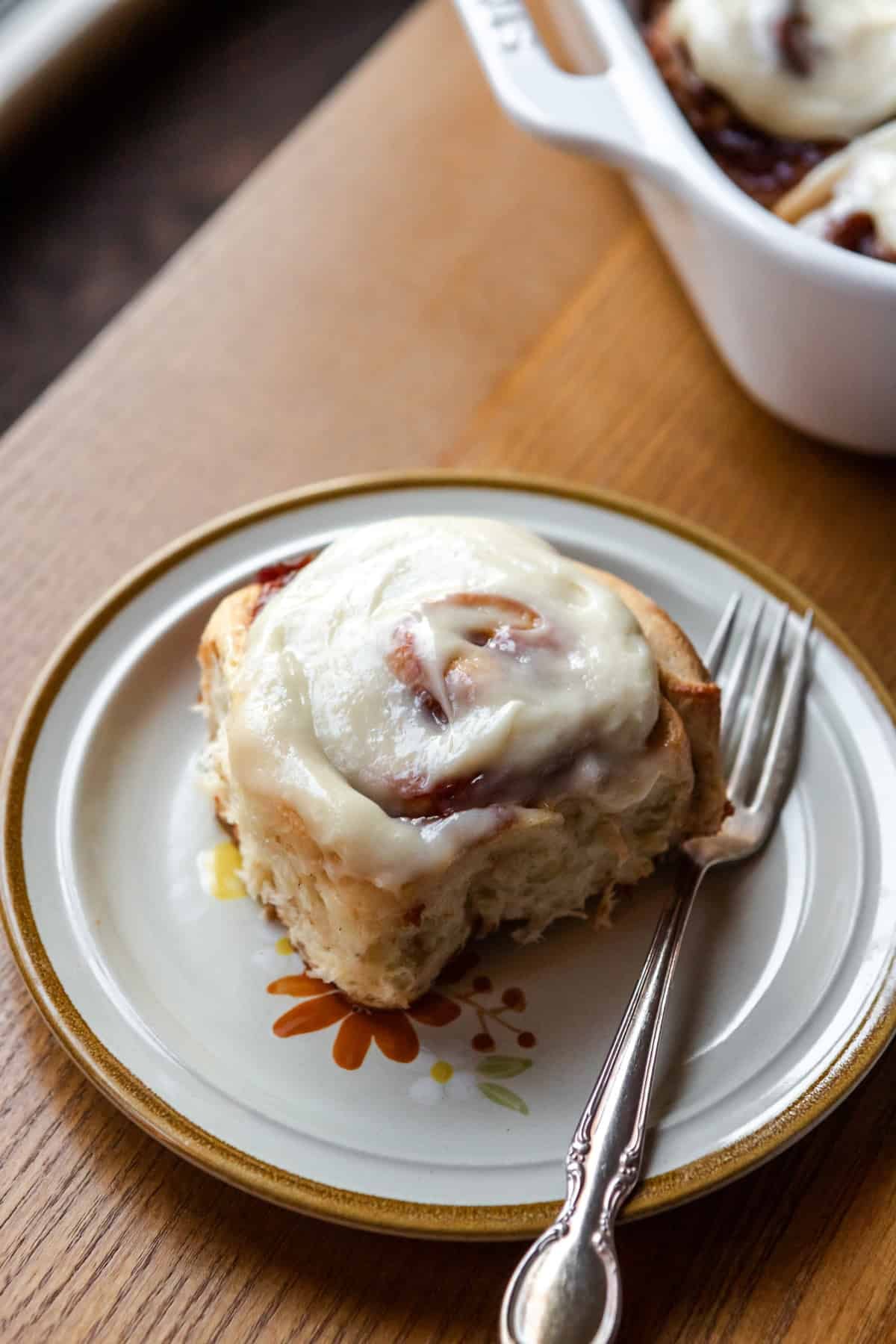 A cinnamon roll on a plate with a fork.