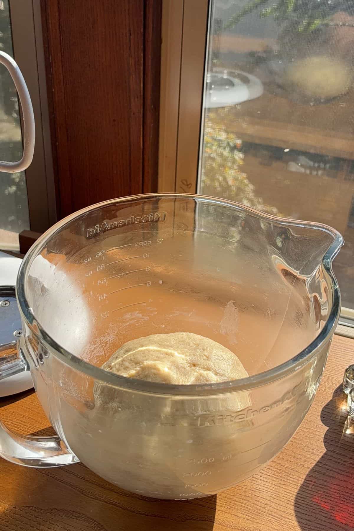 A ball of dough in a large glass bowl.