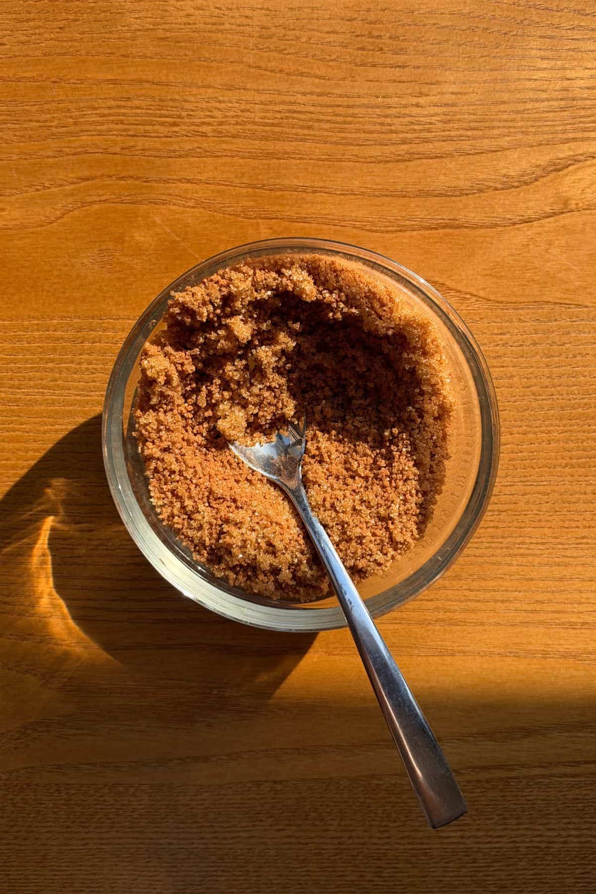 Brown sugar and cinnamon in a small glass bowl with a spoon.