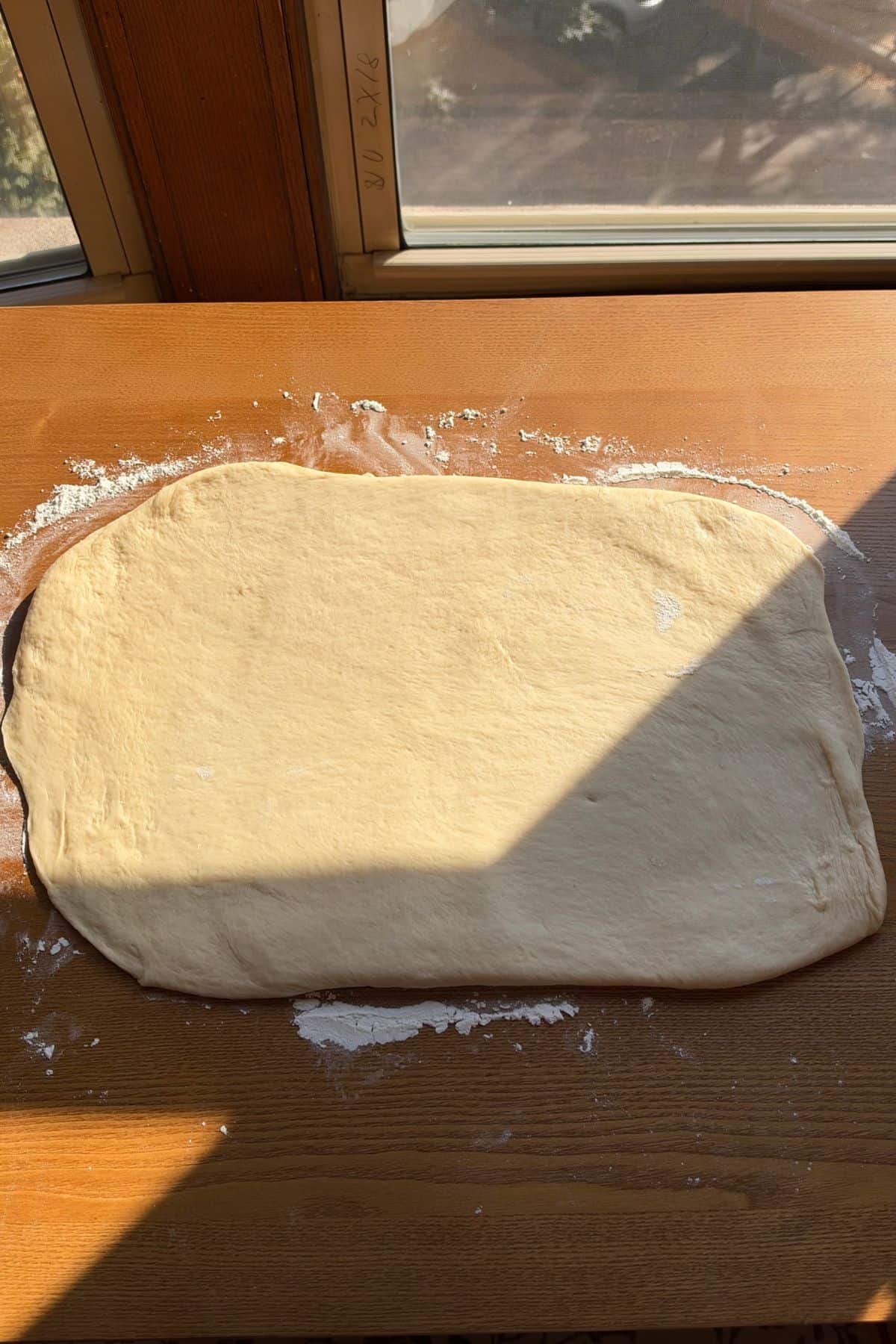 Dough rolled into a rectangle on a wooden surface.