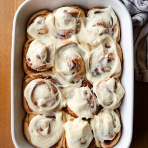 Apple butter cinnamon rolls with maple cream cheese icing in a white baking dish.