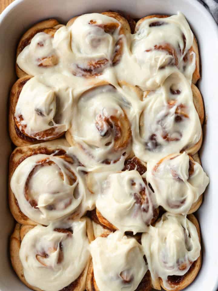 Apple butter cinnamon rolls with maple cream cheese icing in a white baking dish.